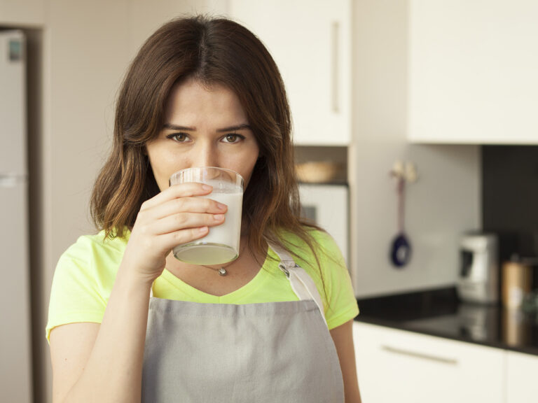 Mujer en cocina bebiendo leche sin lactosa
