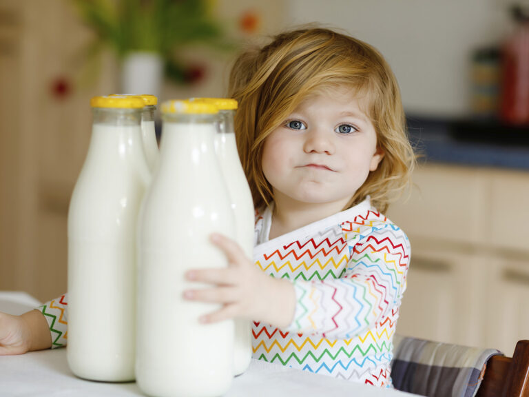 Niña tomando una botella de leche, fuente de calcio y vitamina D esencial en la infancia
