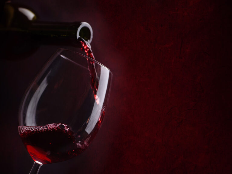 Vino tinto siendo vertido en copa cristal
