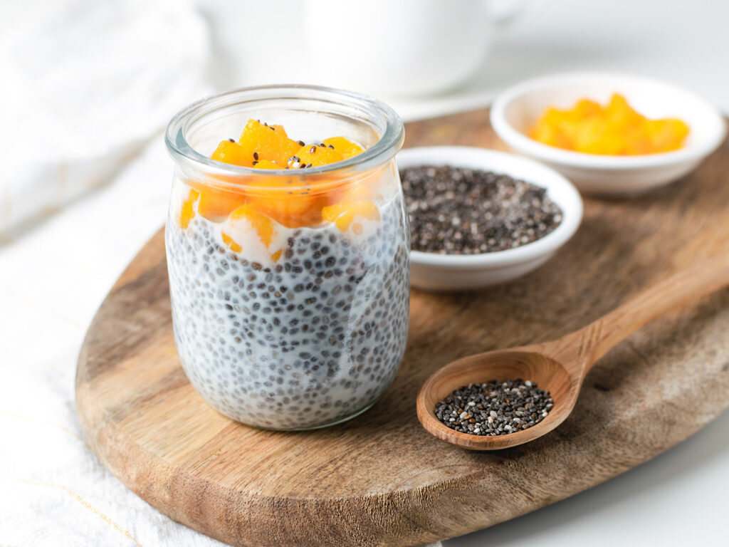 Pudding de semillas de chía con naranja en vaso de cristal y semillas en cuenco