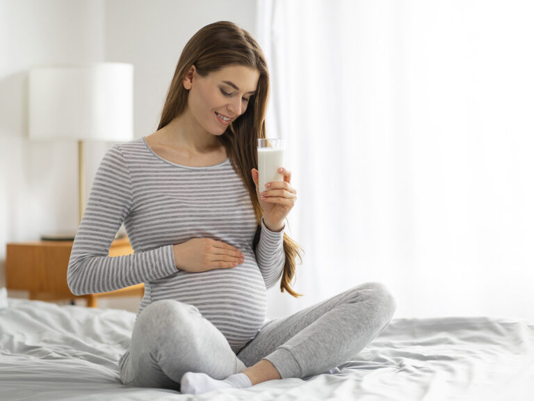 Mujer embarazada con botella de suplemento Omega 3