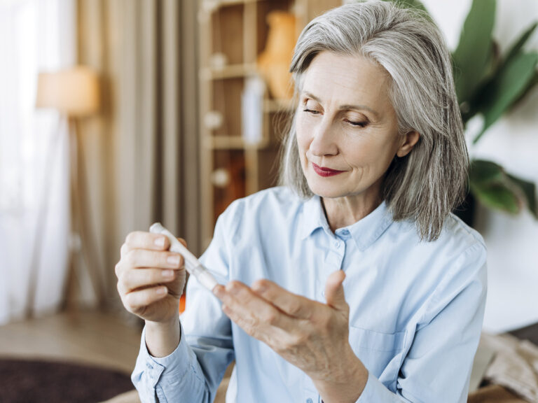 Mujer mayor sosteniendo botella de suplemento Omega 3