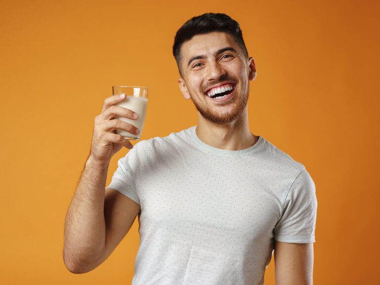 Hombre joven sosteniendo vaso de leche con Omega 3