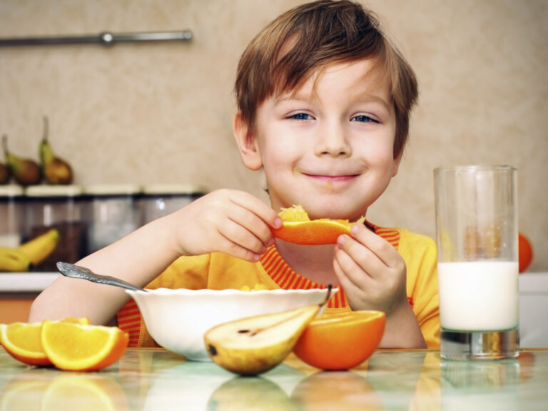 Niño desayunando frutas leche naranja plátano