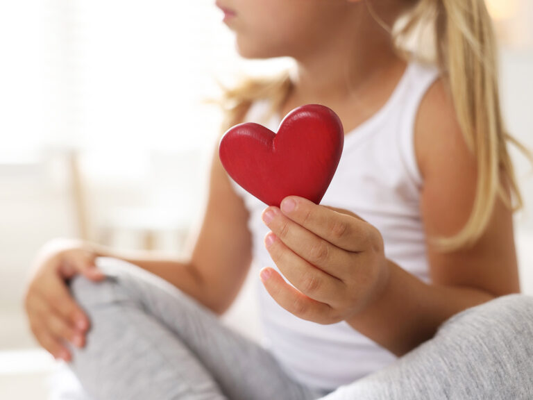 Niña sosteniendo corazón rojo representando salud