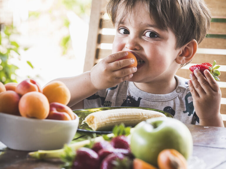 Niño comiendo frutas frescas y fresas