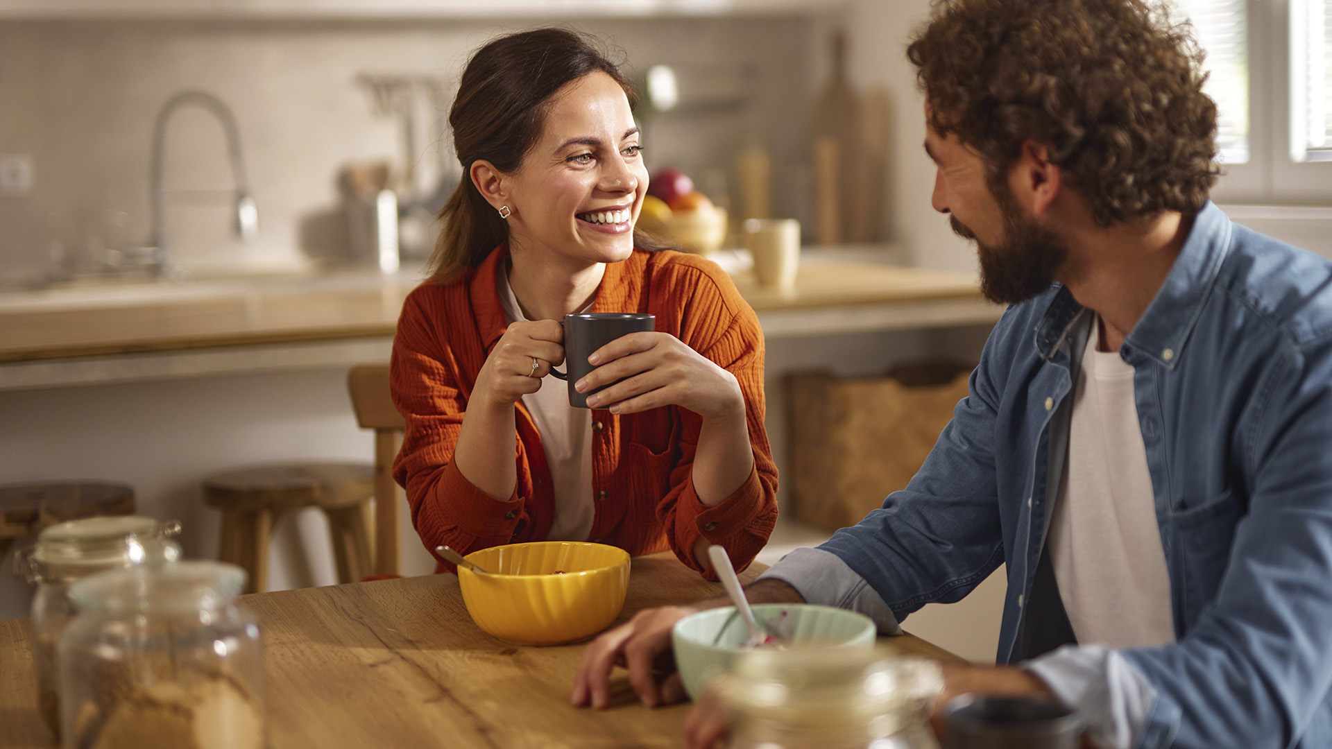 Pareja joven sonriente compartiendo desayuno en cocina