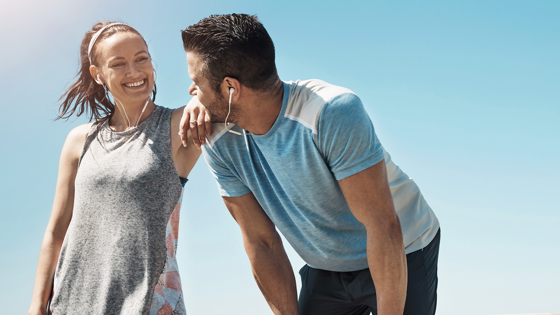 Pareja deportista corriendo juntos al aire libre con auriculares