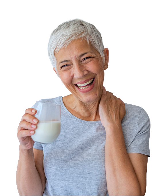 Mujer mayor sonriente sosteniendo vaso de leche blanca