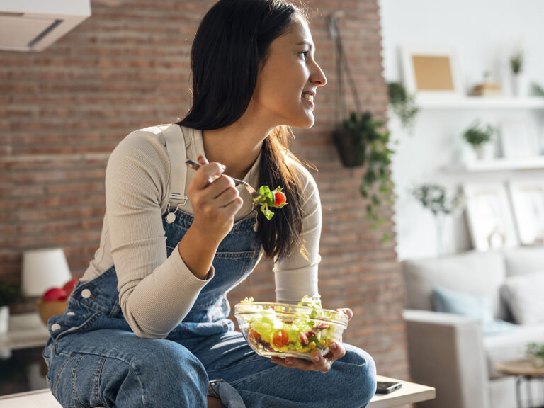 Mujer comiendo ensalada sin lactosa en hogar