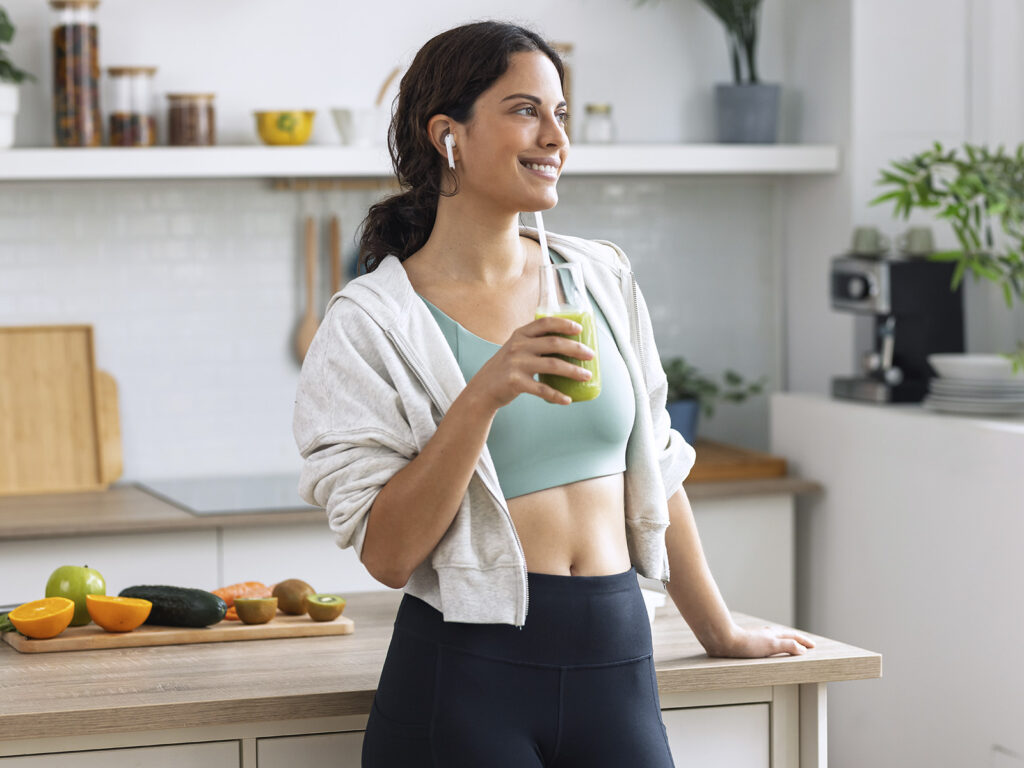 Mujer deportista con manzana verde en cocina moderna