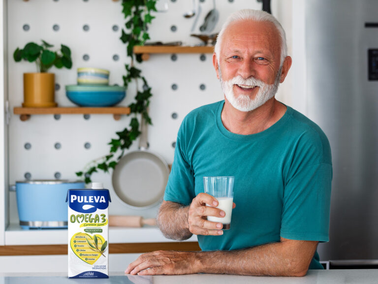 Hombre mayor sosteniendo vaso de leche PULEVA Omega 3