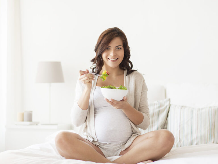 Mujer embarazada comiendo ensalada saludable