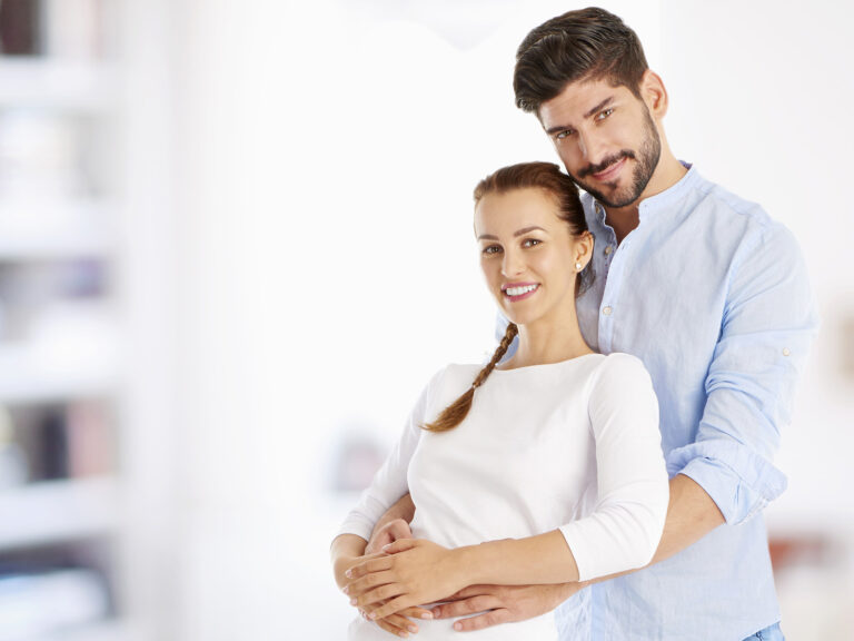 Pareja embarazada abrazada feliz y sonriente