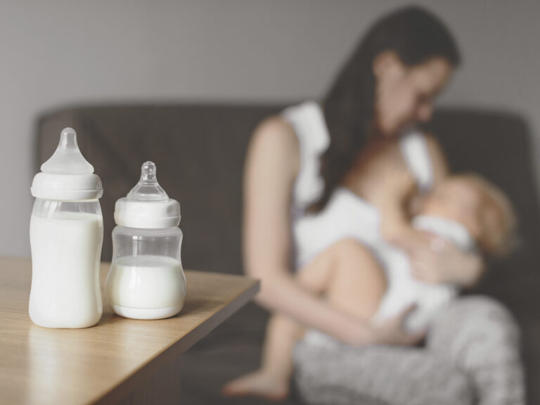 Biberones de leche y madre amamantando a bebé