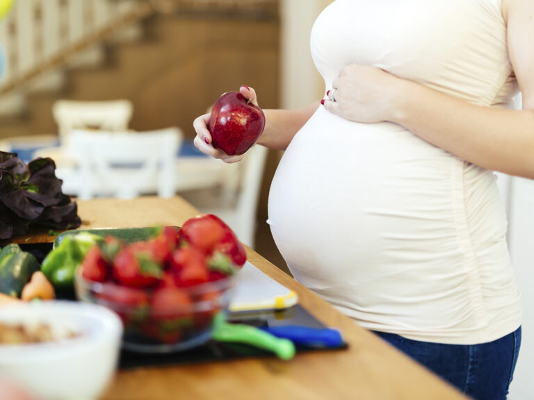 Mujer embarazada comiendo manzana y frutas