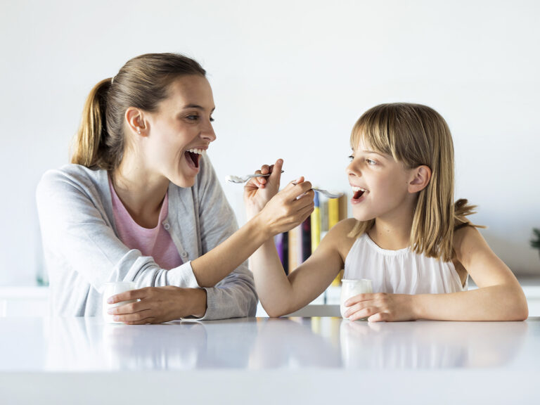 Madre e hija comiendo y sonriendo juntas