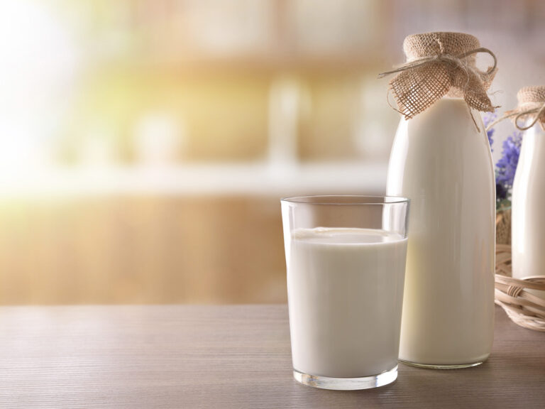 Vaso de leche con botella en mesa de madera