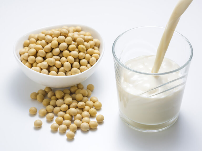 Granos de soja en bol y leche de soja siendo vertida