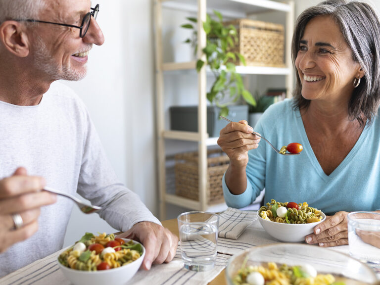 Pareja mayor comiendo ensalada juntos en mesa