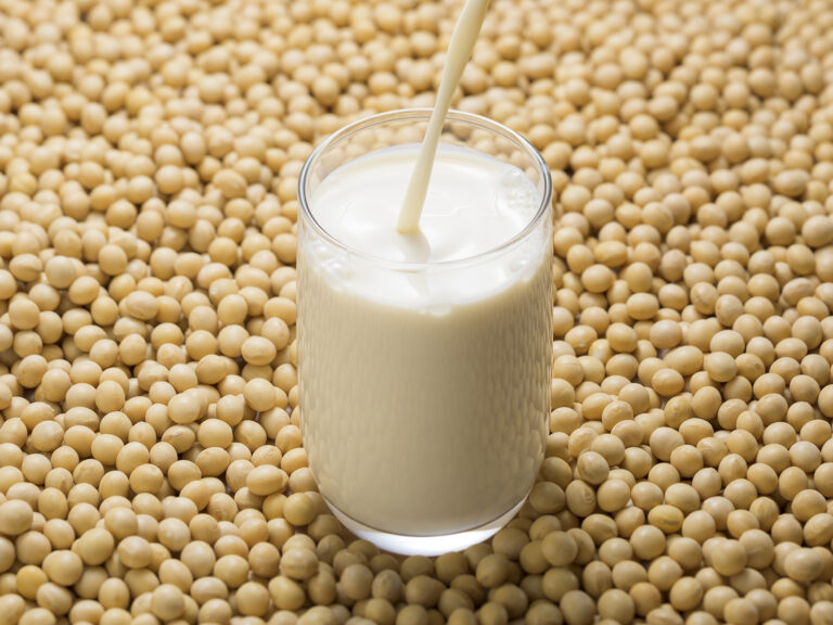 Leche de soja siendo vertida en vaso con granos de soja