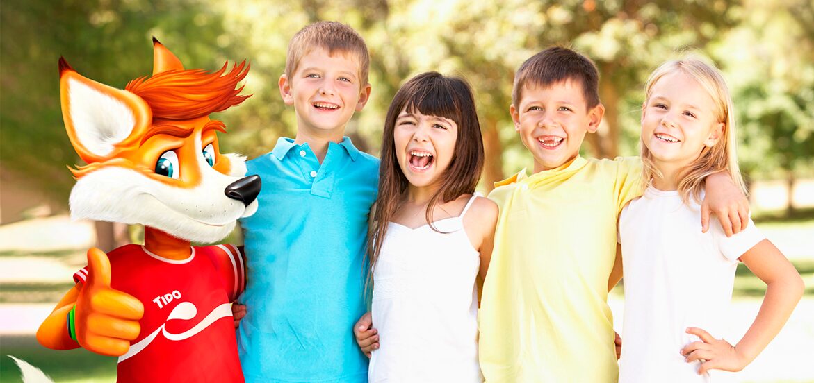 Mascota Tido león de Puleva con niños sonriendo en parque - batidos Puleva